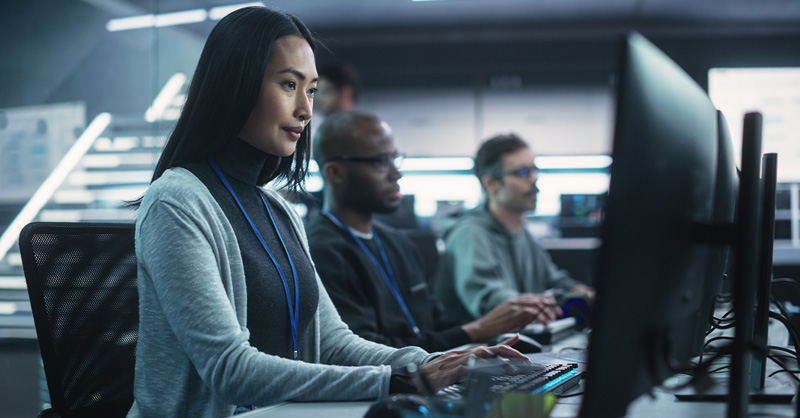 Young Asian Female Software Developer Working on Computer Together with Diverse Creative Colleagues. Data Protection Center with Servers, Storage Hardware and Cyber Security Research