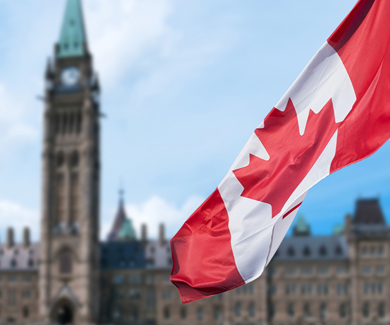Canadian flag waving with Parliament Buildings hill in the background