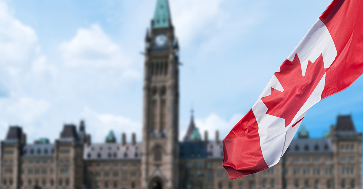 Canadian flag waving with Parliament Buildings hill in the background