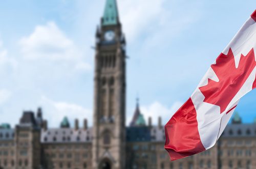 Canadian flag waving with Parliament Buildings hill in the background