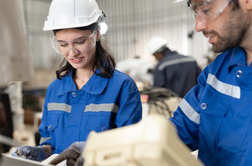 Man-and-woman-engineer-checking-arm-robot-with-remote-control-