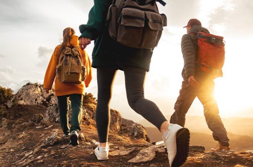 Three-young-hikers-with-small-backpacks-walks-in-sunset-mountains
