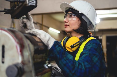 female-engineer-in-safety-gear-working-on-a-machine