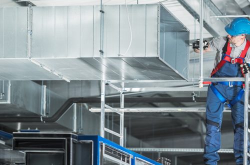 skilled-HVAC-worker-securing-air-duct-in-a-large-warehouse